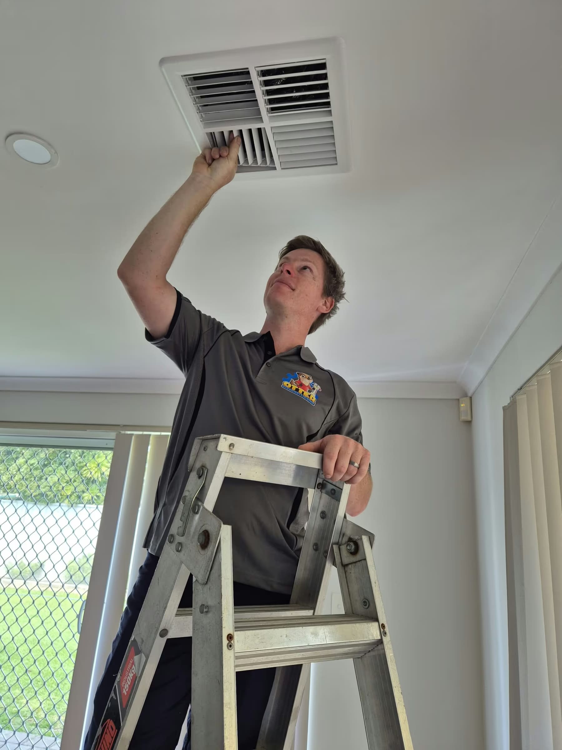 Matt, owner of Otter Air, servicing a ducted air conditioning vent in a Perth home